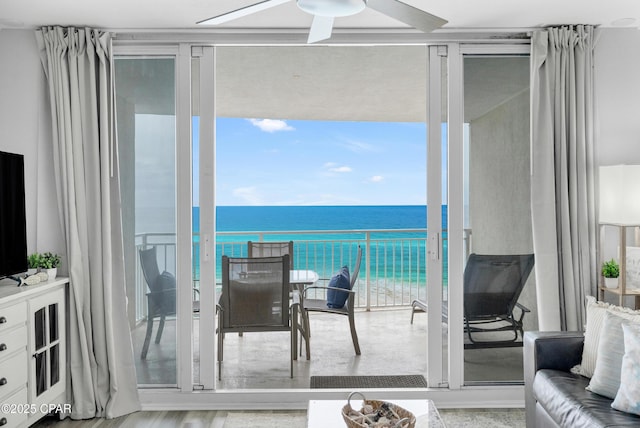 balcony featuring a water view, ceiling fan, and a beach view