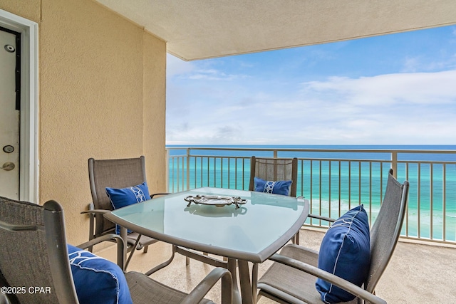 balcony with outdoor dining area and a water view