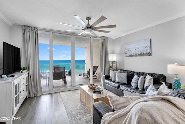 living room with expansive windows, light wood finished floors, a ceiling fan, and crown molding