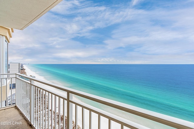 balcony with a water view and a view of the beach