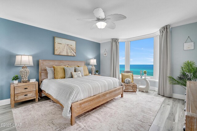 bedroom with a water view, crown molding, baseboards, and wood finished floors