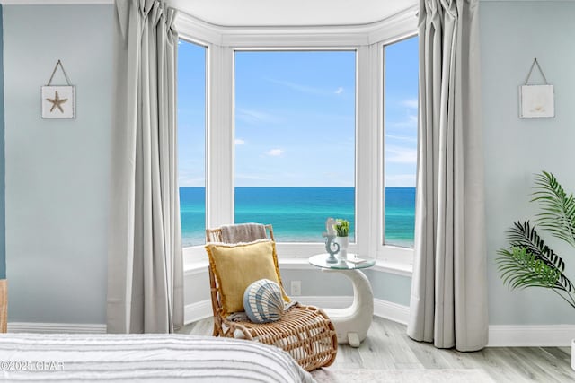 bedroom with a water view, baseboards, and wood finished floors