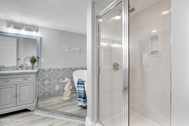 bathroom featuring a stall shower, a soaking tub, vanity, and wood finished floors