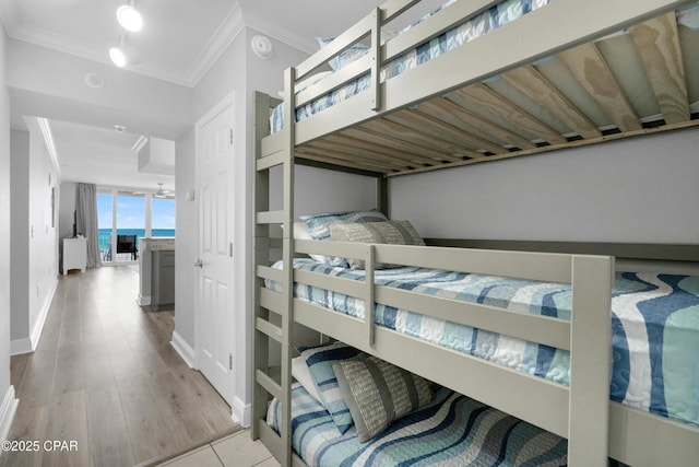 bedroom with baseboards, ornamental molding, and wood finished floors