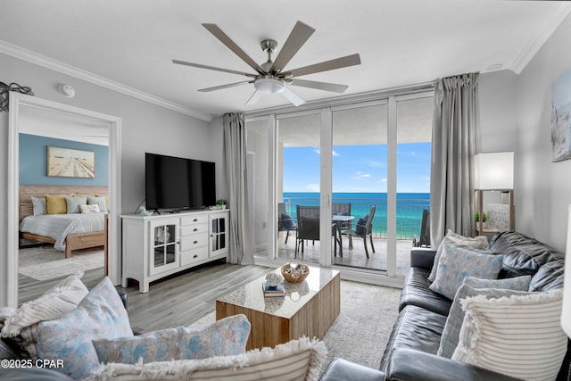 living area with ceiling fan, floor to ceiling windows, crown molding, and wood finished floors