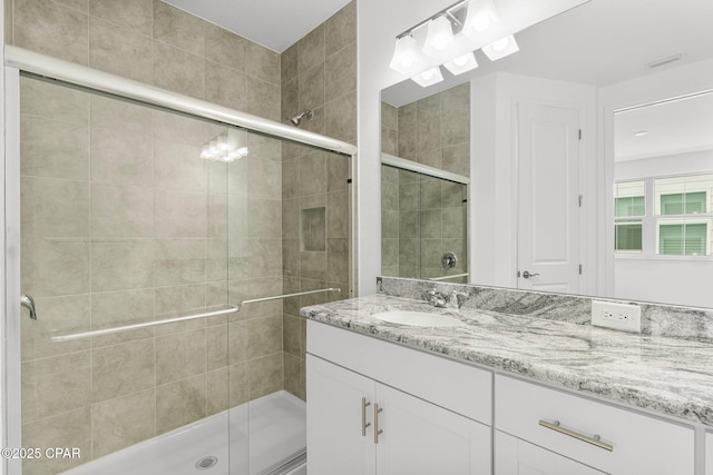 bathroom featuring a shower stall, vanity, and visible vents