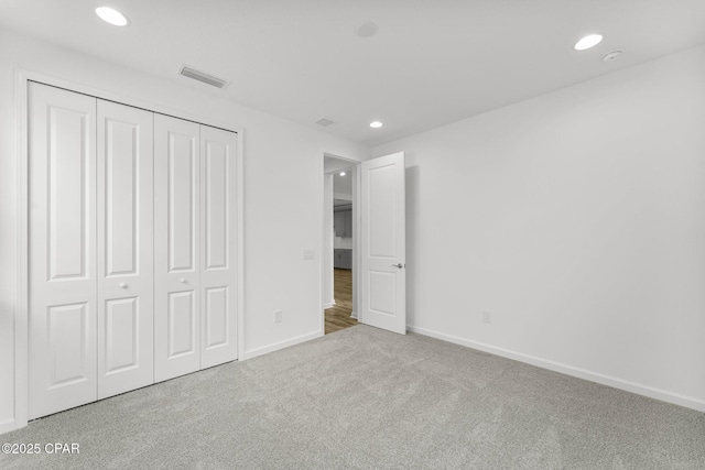 unfurnished bedroom featuring recessed lighting, carpet, visible vents, and a closet