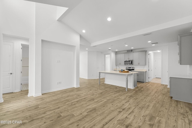 unfurnished living room with baseboards, recessed lighting, high vaulted ceiling, light wood finished floors, and a sink
