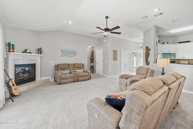 living area featuring visible vents, light colored carpet, lofted ceiling, ceiling fan, and a fireplace