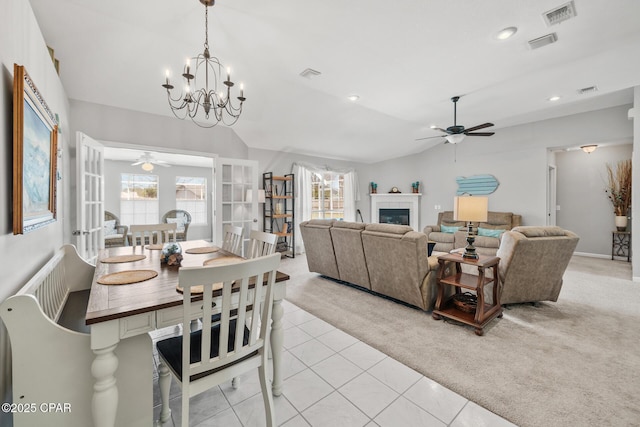 dining room with lofted ceiling, visible vents, a tiled fireplace, and light colored carpet