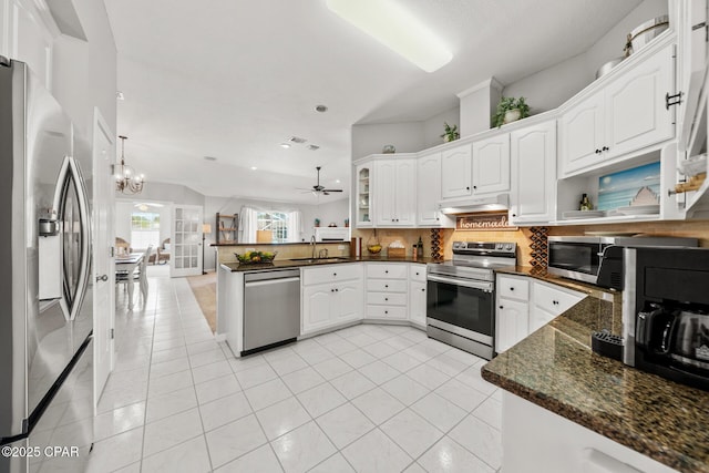 kitchen featuring under cabinet range hood, stainless steel appliances, a peninsula, white cabinetry, and tasteful backsplash