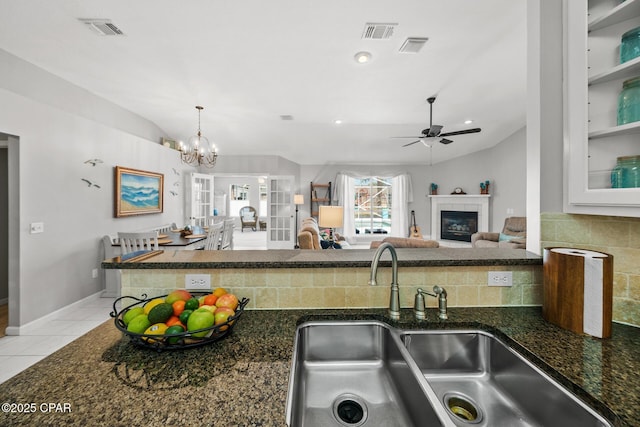 kitchen featuring visible vents, a sink, a fireplace, and light tile patterned floors