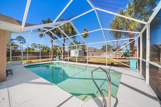 view of pool with an outbuilding, a playground, a fenced backyard, a storage unit, and a patio area