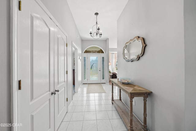 entryway with an inviting chandelier and light tile patterned floors