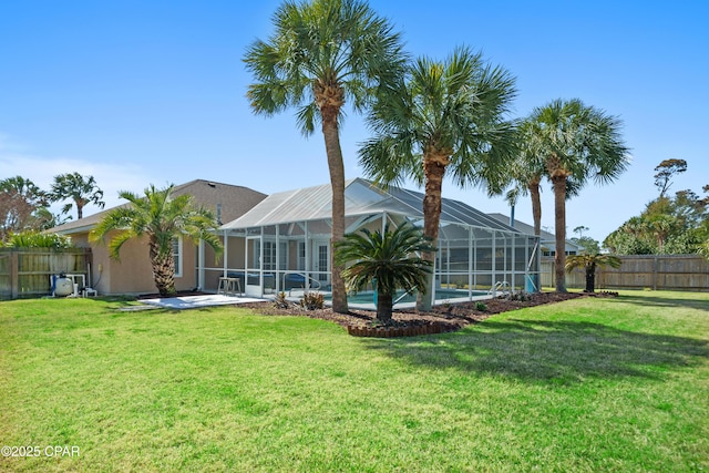 rear view of property featuring glass enclosure, a yard, and a fenced backyard