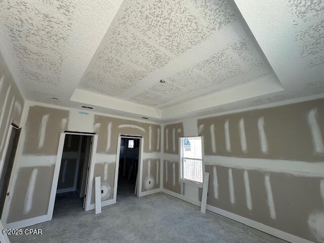 unfurnished bedroom featuring a tray ceiling and a textured ceiling