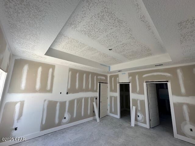 unfurnished bedroom with a textured ceiling and a tray ceiling