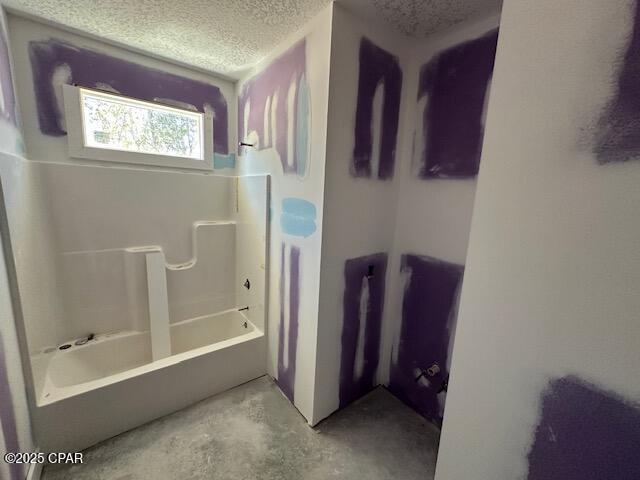 full bath with unfinished concrete floors, tub / shower combination, and a textured ceiling