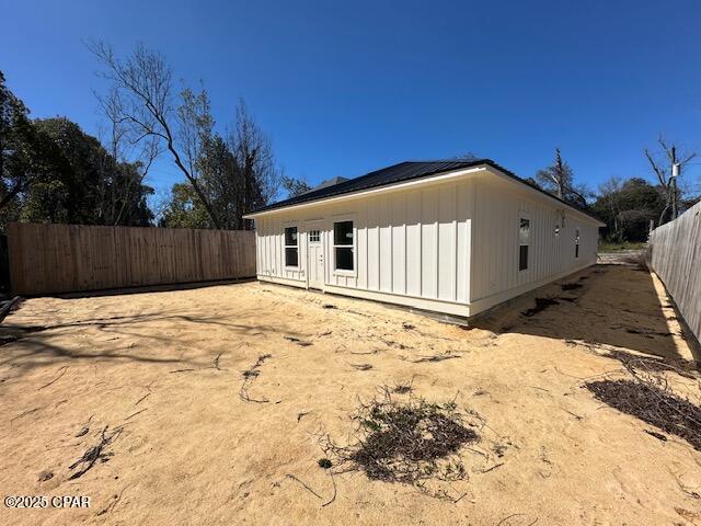 rear view of house with board and batten siding and fence