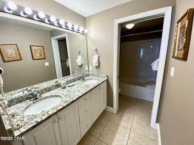 bathroom with toilet, double vanity, a sink, and tile patterned floors