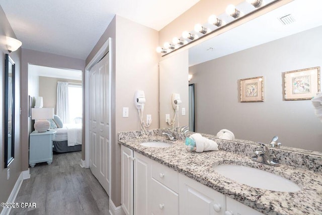 full bathroom with double vanity, wood finished floors, visible vents, and a sink