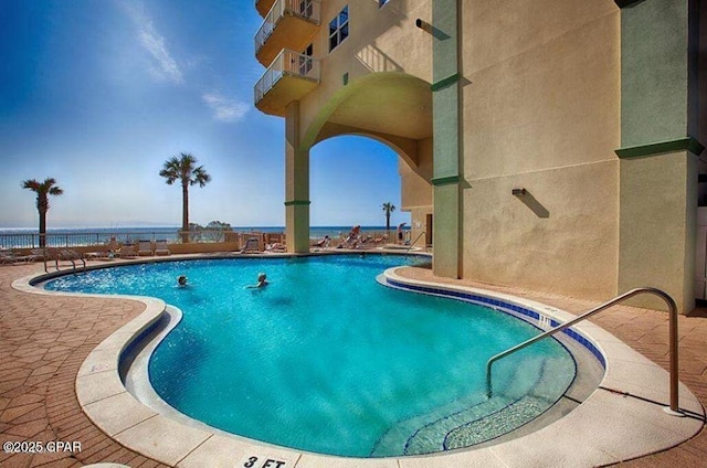 community pool with a water view and a patio area