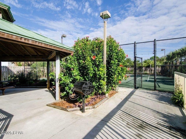 view of patio featuring a tennis court, area for grilling, a gazebo, and fence