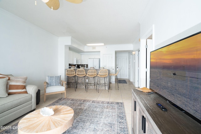 living area with crown molding, light tile patterned floors, and baseboards