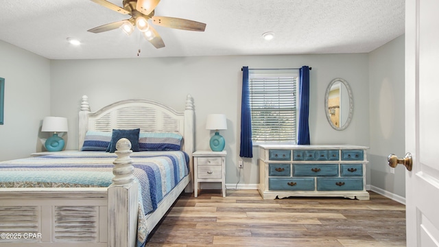 bedroom featuring a ceiling fan, a textured ceiling, baseboards, and wood finished floors