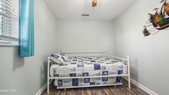 bedroom featuring baseboards, visible vents, ceiling fan, wood finished floors, and a textured ceiling