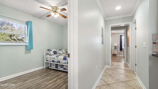 hall featuring a textured ceiling, baseboards, and crown molding