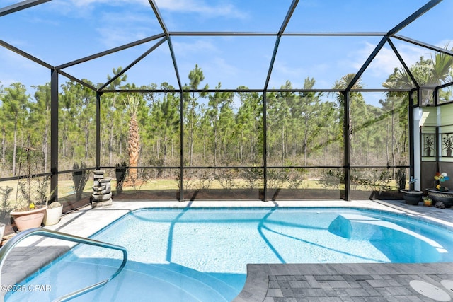 outdoor pool with glass enclosure, a patio, and a view of trees