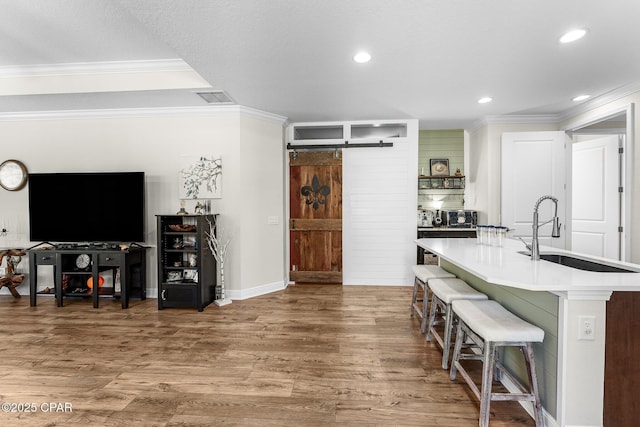 kitchen featuring wood finished floors, visible vents, a sink, and a barn door