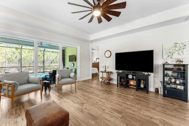 living room with crown molding, baseboards, a ceiling fan, and light wood-style floors