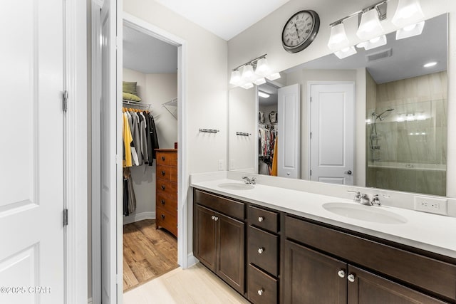 bathroom with a sink, double vanity, a shower stall, and visible vents