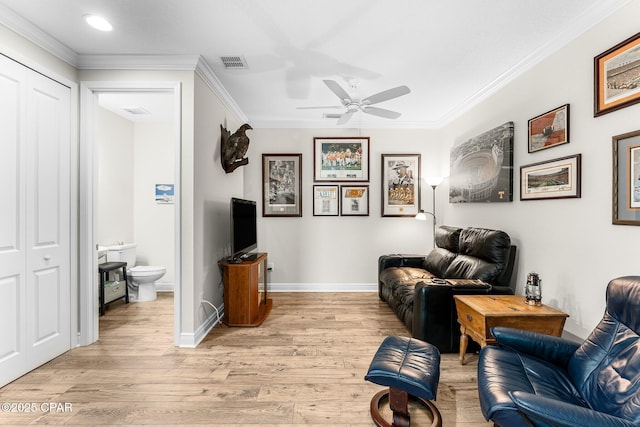 sitting room featuring light wood-style floors, baseboards, visible vents, and ornamental molding