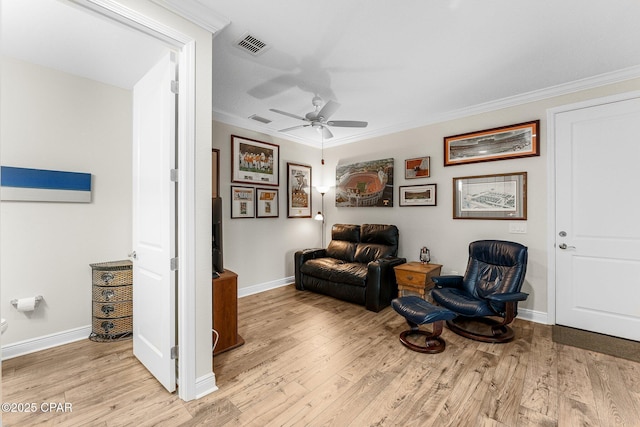 sitting room featuring crown molding, light wood-style flooring, and baseboards