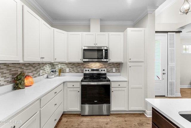 kitchen featuring appliances with stainless steel finishes, light countertops, crown molding, and light wood-style flooring