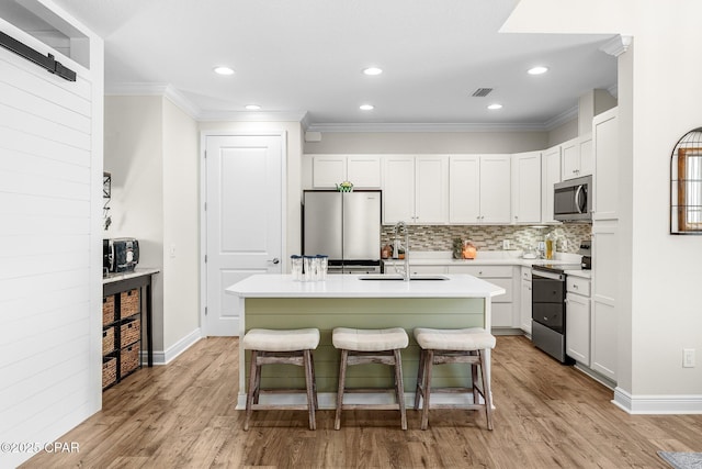 kitchen featuring stainless steel appliances, light wood-style flooring, a sink, and visible vents