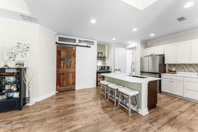 kitchen with a breakfast bar, visible vents, a sink, and a barn door