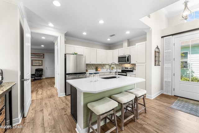 kitchen with decorative backsplash, appliances with stainless steel finishes, a breakfast bar, light countertops, and a sink