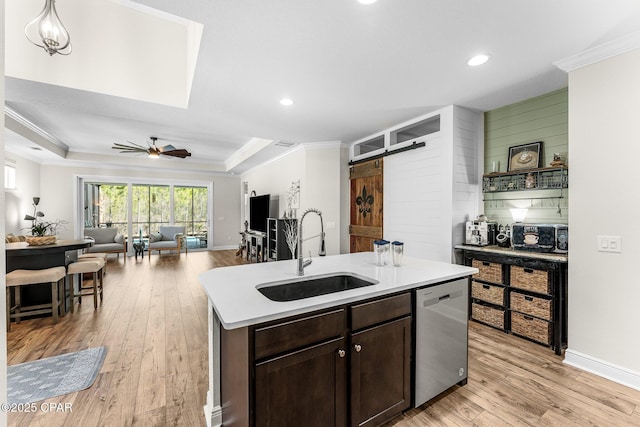 kitchen with stainless steel dishwasher, a barn door, a sink, and crown molding