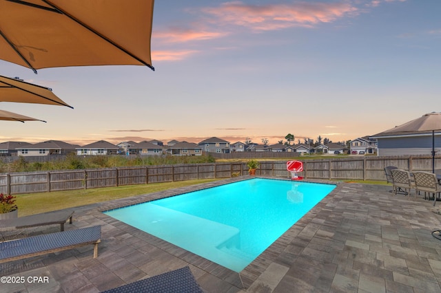 view of swimming pool featuring a patio, a yard, a fenced backyard, and a residential view