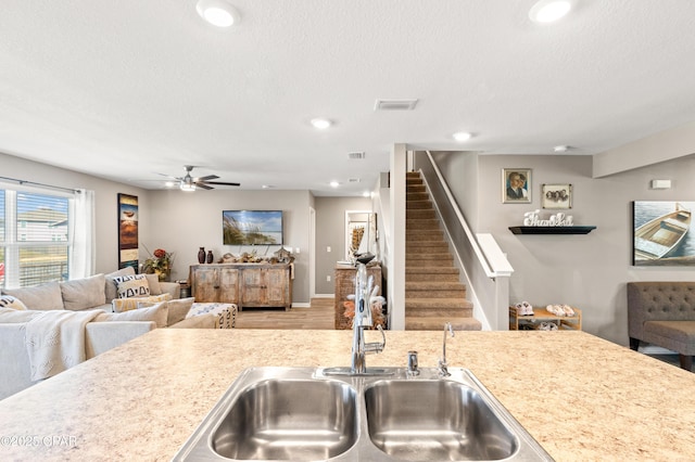 kitchen with visible vents, open floor plan, light countertops, a textured ceiling, and a sink