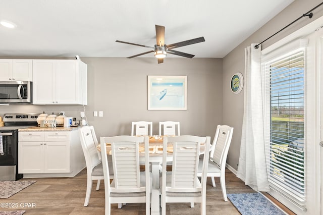 dining space featuring baseboards, light wood-style flooring, and a ceiling fan