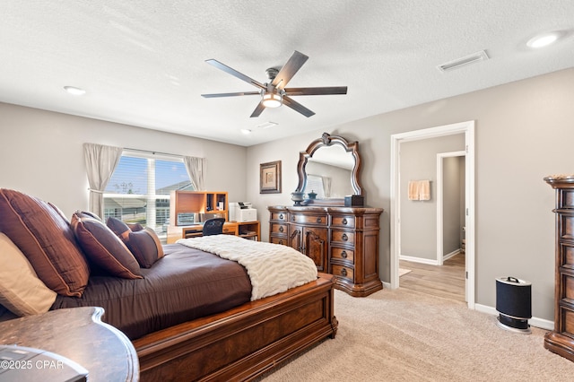 bedroom featuring a textured ceiling, baseboards, visible vents, and light carpet