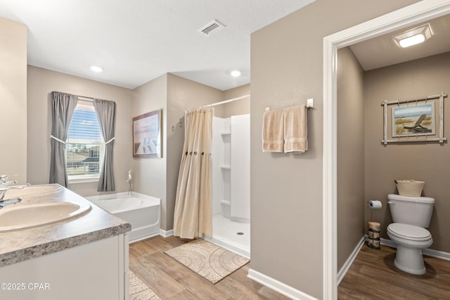 bathroom with a stall shower, wood finished floors, visible vents, and a sink