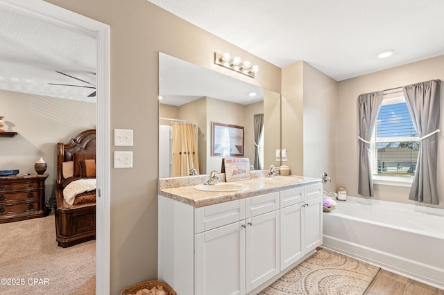 ensuite bathroom with a sink, double vanity, a bath, and ensuite bathroom