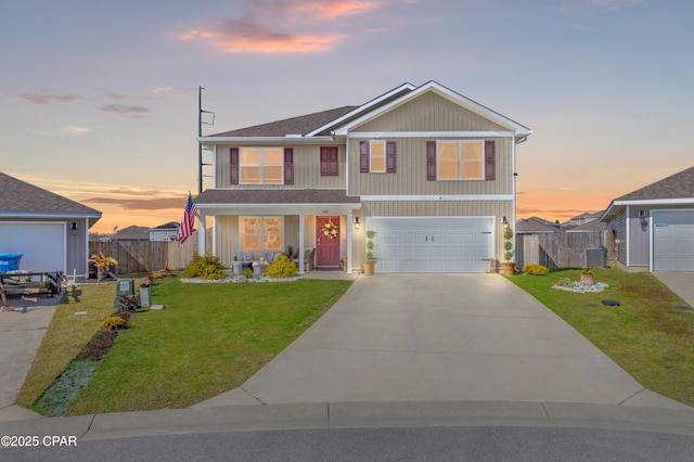 traditional-style house with a garage, a lawn, driveway, and fence