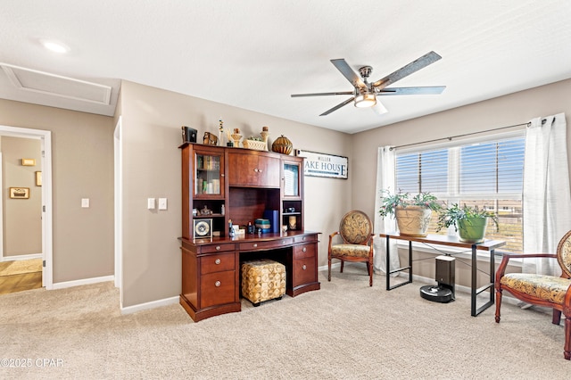 office space featuring light carpet, attic access, baseboards, and a ceiling fan